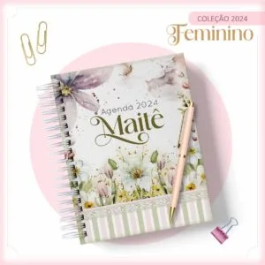 Uma agenda espiral com estampa floral e uma caneta sobre fundo branco decorado.