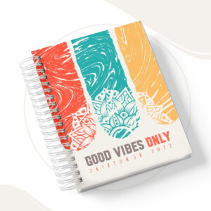Caderno espiral com capa colorida decorada com formas geométricas e texto motivacional.