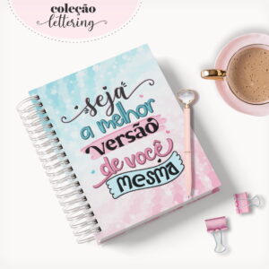 Caderno espiral com arte lettering, caneta rosa, xícara de café e clips.