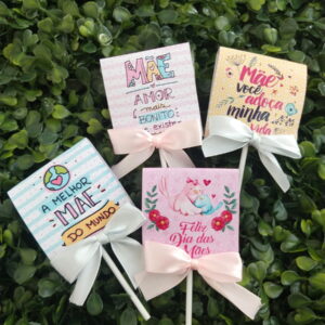 Quatro tags decoradas sobre o Dia das Mães com laços de fita sobre folhagem verde