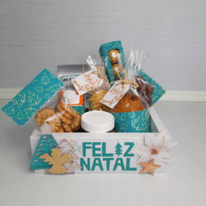 Cesta de Natal branca decorada com doces, biscoitos e bebida.