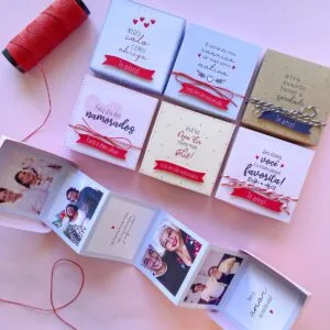 Caixinhas decoradas abertas com fotos e mensagens românticas ao lado de carretel de linha vermelha.