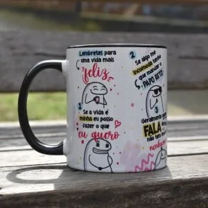 Caneca branca com alça preta e ilustrações estilo meme com frases motivacionais engraçadas.