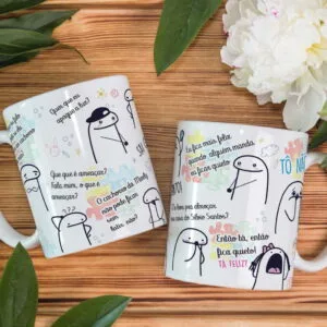 Duas canecas brancas de cerâmica com desenhos estilo cartoon em uma mesa de madeira.