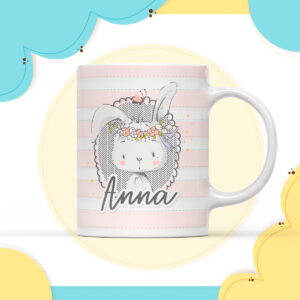 Caneca branca com ilustração de coelho e nome "Anna" em fundo decorativo.