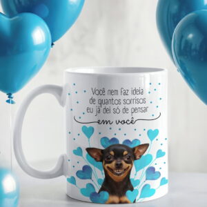 Caneca branca com estampa de cachorro sorrindo, corações azuis e balões ao fundo.