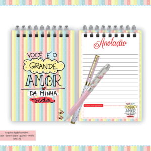 Caderno colorido listrado com frase motivacional e duas canetas em cima.