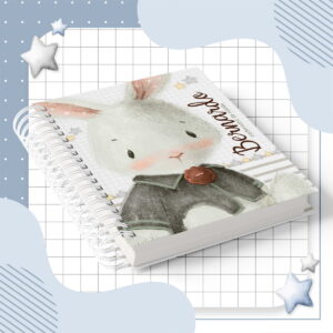 Caderno espiral com ilustração de coelho sobre fundo quadriculado e estrelas decorativas.
