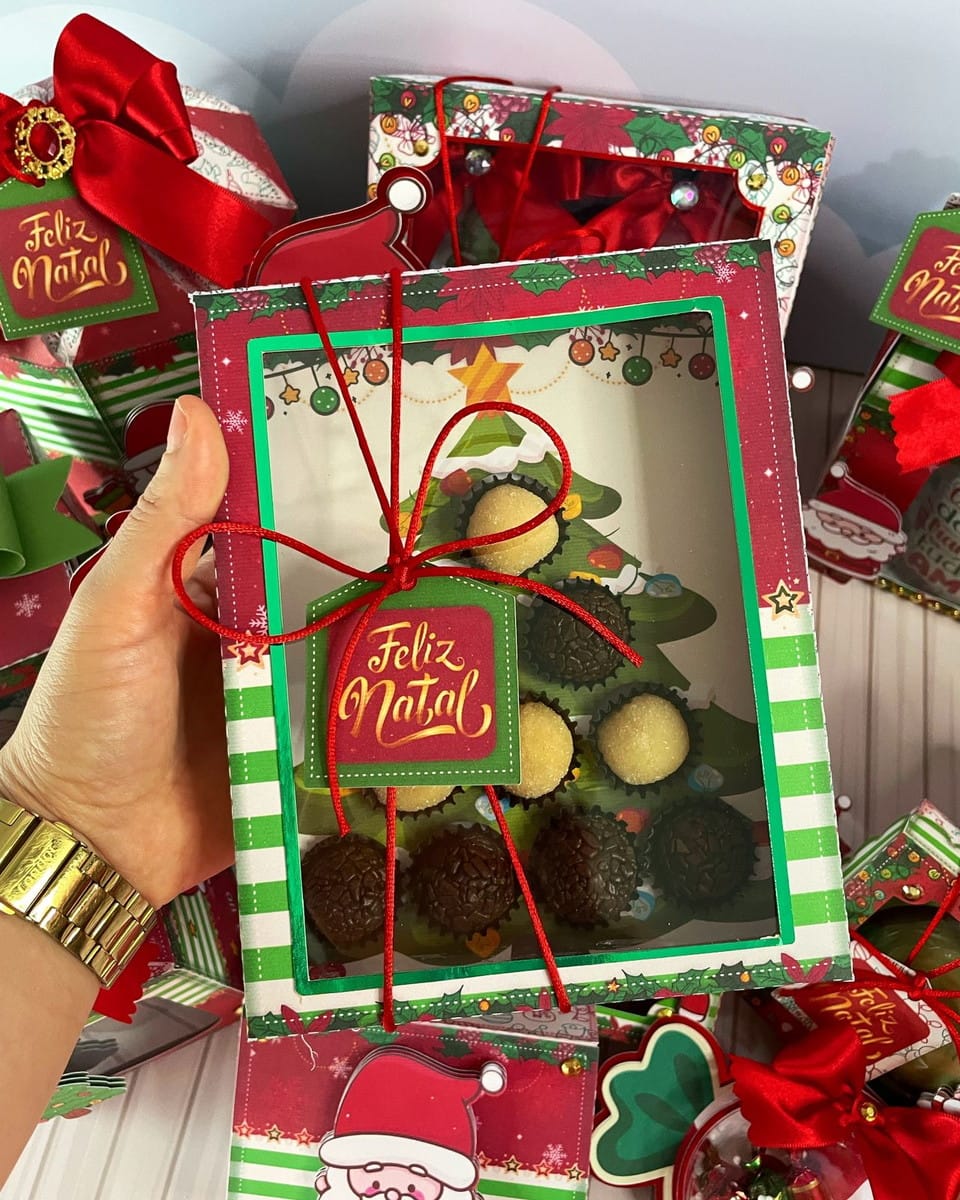 Caixa Árvore de Natal para Doces em PDF e Studio 3 Mão segurando uma caixa decorada de Natal com doces redondos dentro.