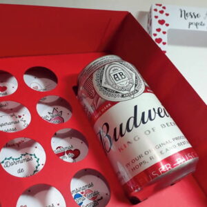 Caixa vermelha decorada com lata de bebida e pequenos bilhetes redondos.