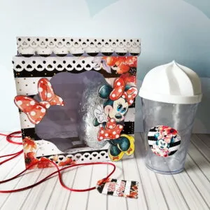 Caixa decorada com tema de personagem infantil e um copo transparente ao lado.