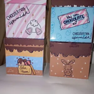 Quatro caixas decoradas com temas de Páscoa e chocolate em fundo neutro