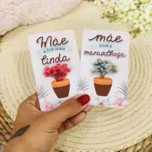 Card com Florzinha Dia das Mães - Arquivo Digital 16 Mão segurando dois cartões decorados com mensagens em português e vasos de flores.