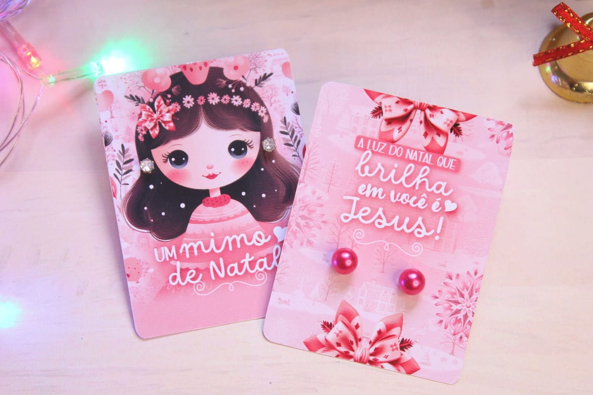 Card Natal para Brincos Rosa com 8 Modelos A4 2 Dois cartões rosa decorados com ilustrações temáticas e brincos fixados sobre eles.
