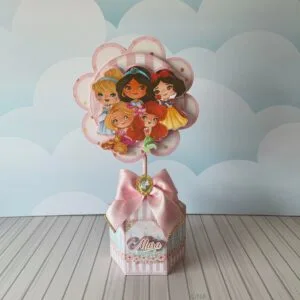 Centro de Mesa Princesas Menina - Arquivo Digital 11 Topo de bolo artesanal com ilustração de várias personagens femininas e laço rosa.