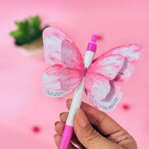 Kit Digital Outubro Rosa para Lembrancinhas e Mimos 25 Mão segurando caneta branca e rosa com asas de borboleta de papel.