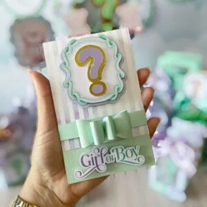 Mão segurando cartão de papel decorado com ponto de interrogação e laço verde.