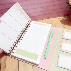 Planner aberto com páginas de planejamento anual, caneta verde e notas adesivas.