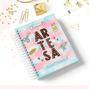 Caderno espiral colorido com desenhos de artesanato e fundo em tons pastéis.