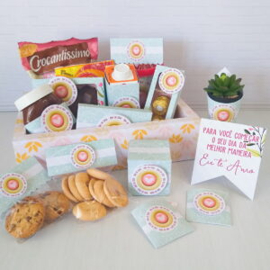 Cesta de presente decorada com diversos doces, biscoitos e um cartão com mensagem.