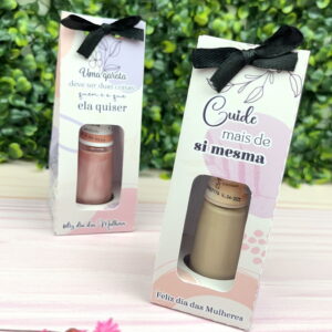 Duas caixas decoradas com esmaltes dentro e laços pretos sobre fundo verde.