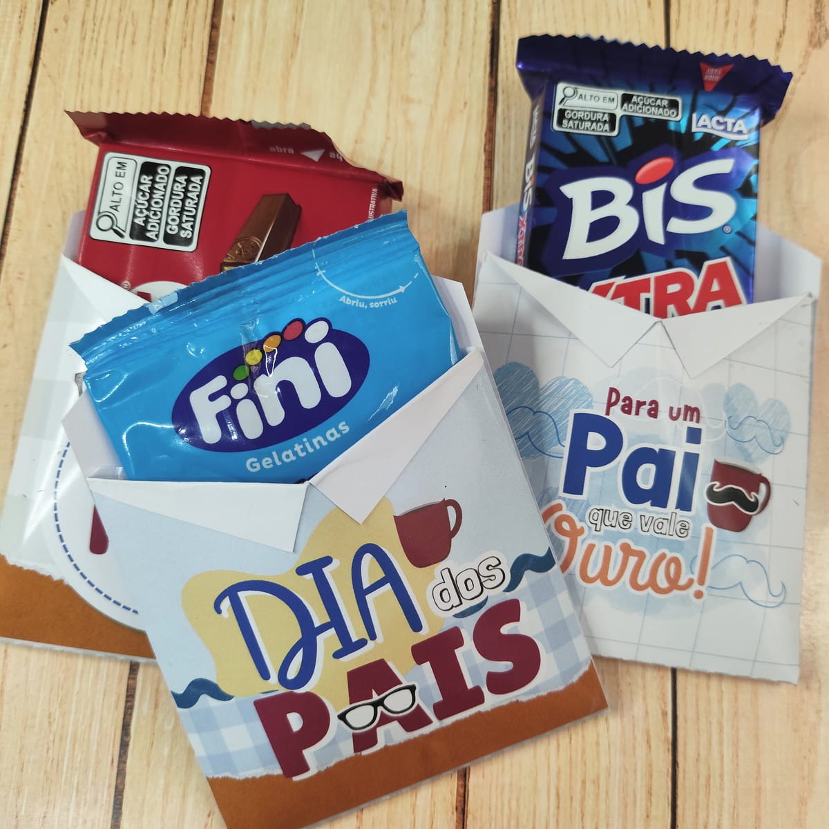 Kit Digital Dia dos Pais Religioso para Imprimir 4 Pequenas sacolas de papel personalizadas com doces para o Dia dos Pais em superfície de madeira.