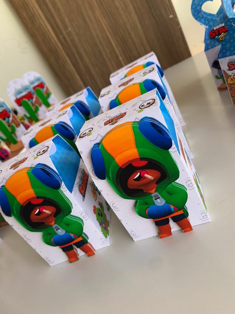 Kit Digital Festa Brawl Stars com Caixas para Lembrancinhas 2 Várias caixinhas de papel decoradas com personagem infantil de capuz verde e laranja.