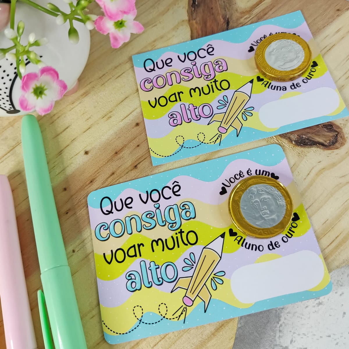 Kit digital mimos formatura escolar com arquivos PNG 3 Dois cartões coloridos com textos motivacionais, lápis em formato de foguete e moedas.