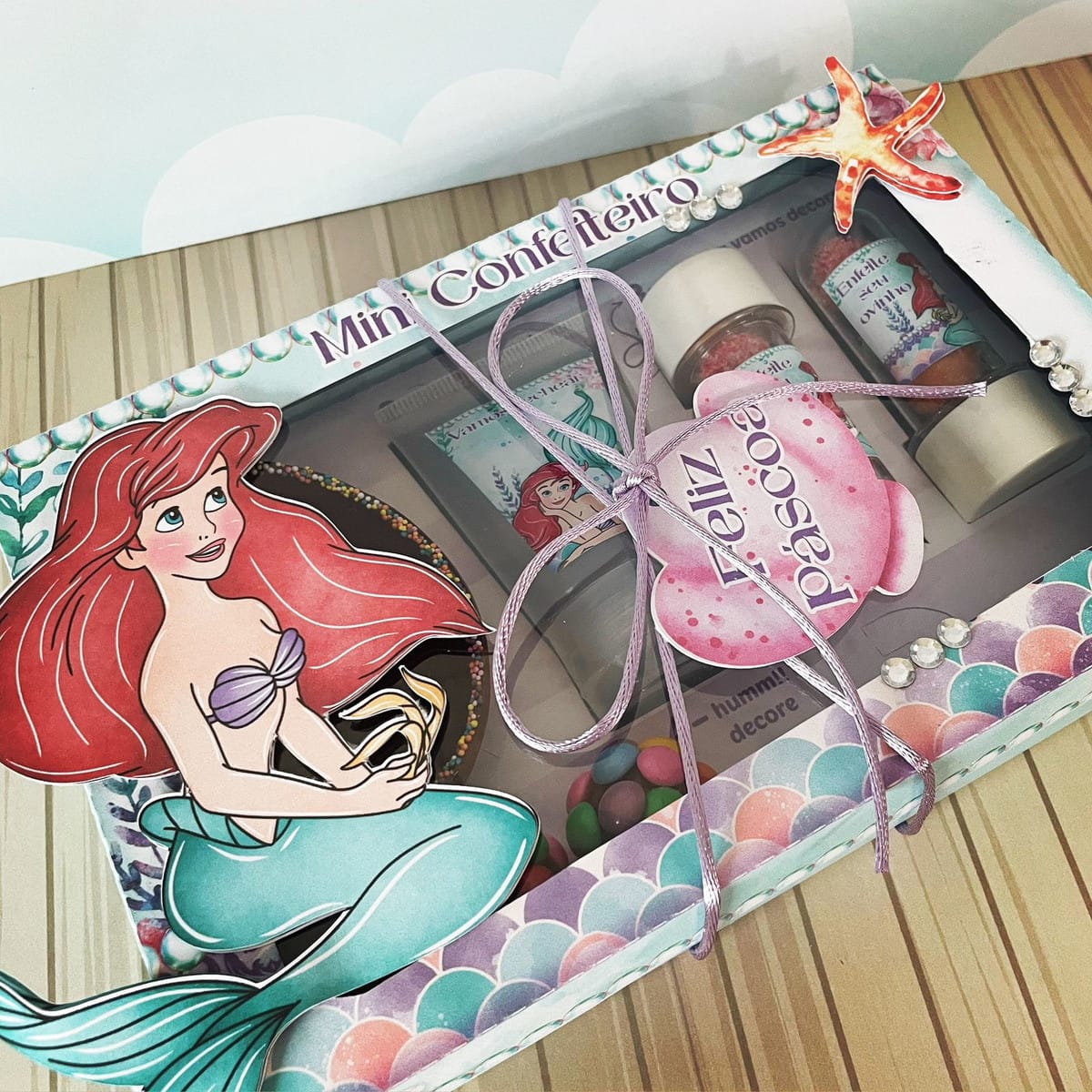 Kit Digital Mini Confeiteiro Ariel em PDF e Studio 4 Caixa decorada com tema de sereia contendo doces e confeitos variados.