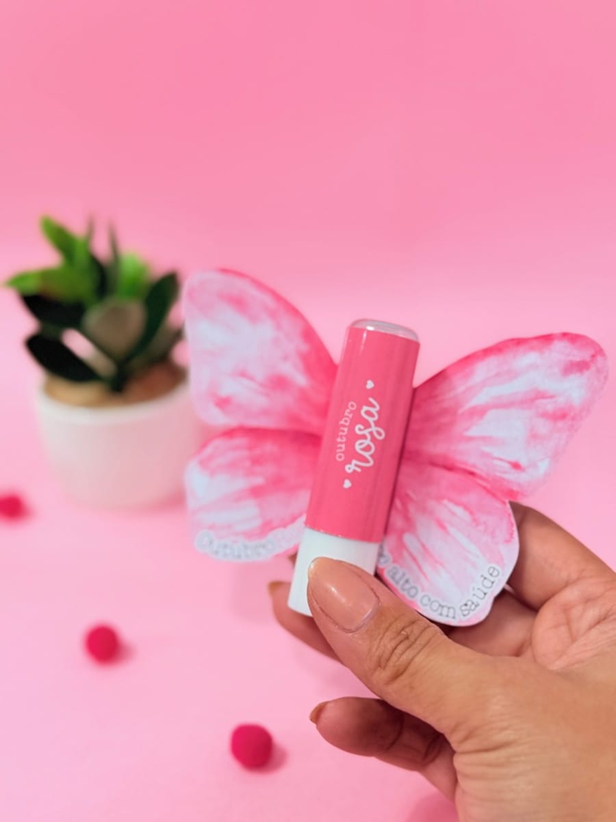 Kit Digital Outubro Rosa para Lembrancinhas e Mimos 2 Batom labial rosa e borboleta de papel sendo segurados, com texto 'Outubro Rosa'.