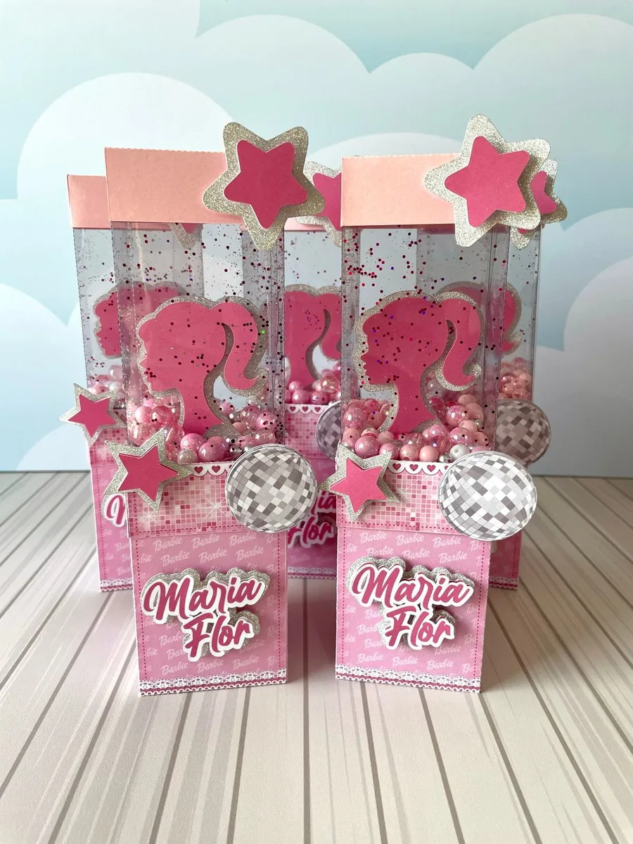 Kit Festa Barbie Luxo - Arquivo Digital 3 Caixas de lembrancinhas transparentes decoradas com estrelas e silhuetas rosas sobre fundo azul.