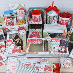 Vários kits de presentes personalizados com temática natalina dispostos sobre uma mesa branca.