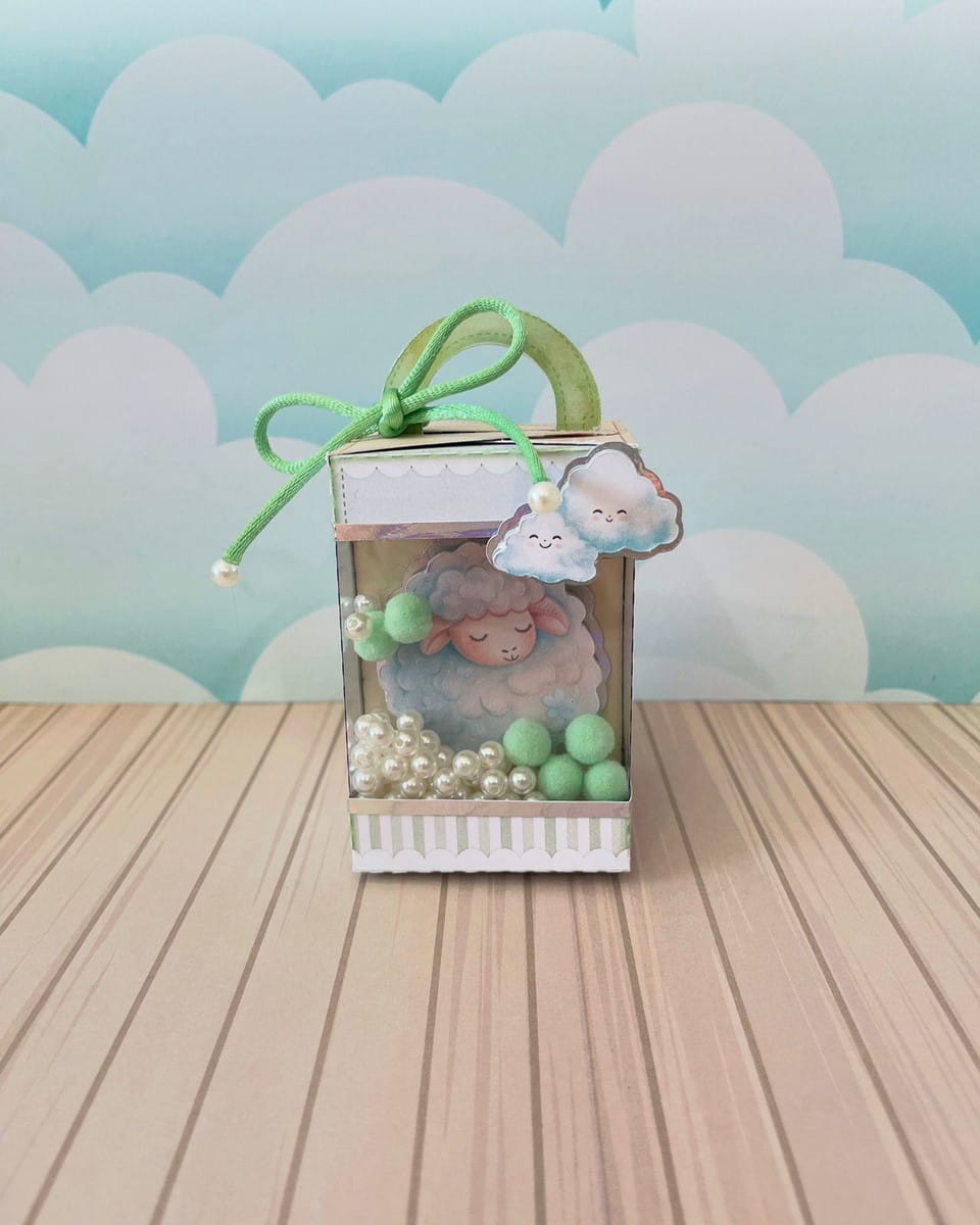 Kit Festa Ovelhinha Verde Luxo em Studio e PDF para Editar 2 Caixa decorativa transparente com ovelha, pérolas brancas, pompons verdes, laço.