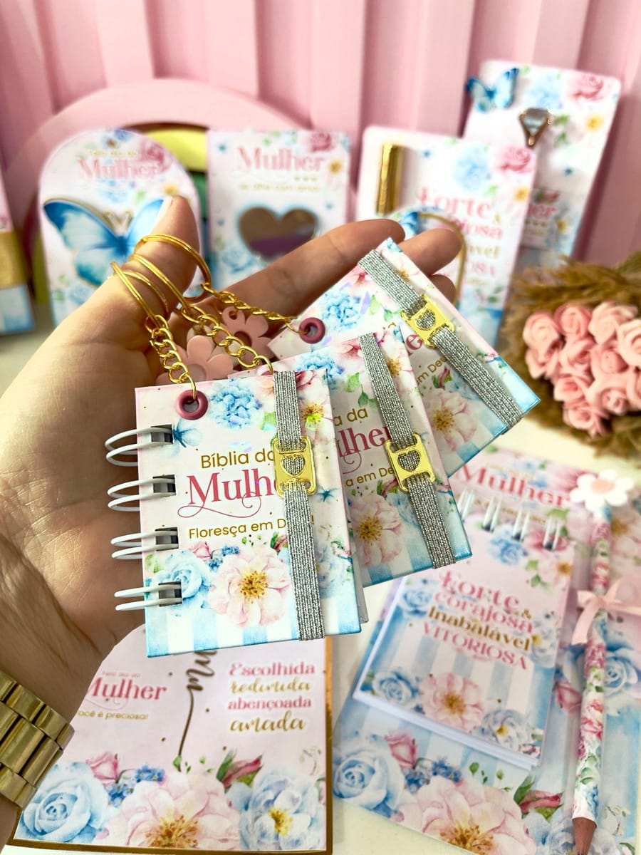 Kit Digital Dia da Mulher 2026 para Lembrancinhas 5 Mão segurando mini-bíblia e cadernos com design floral azul e rosa.