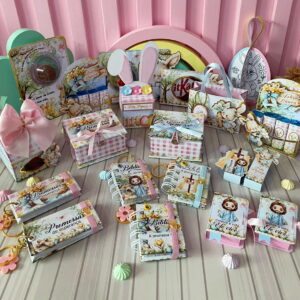 Variedades de lembrancinhas e embalagens decoradas com temas de Páscoa e religiosos, em tons pastel.