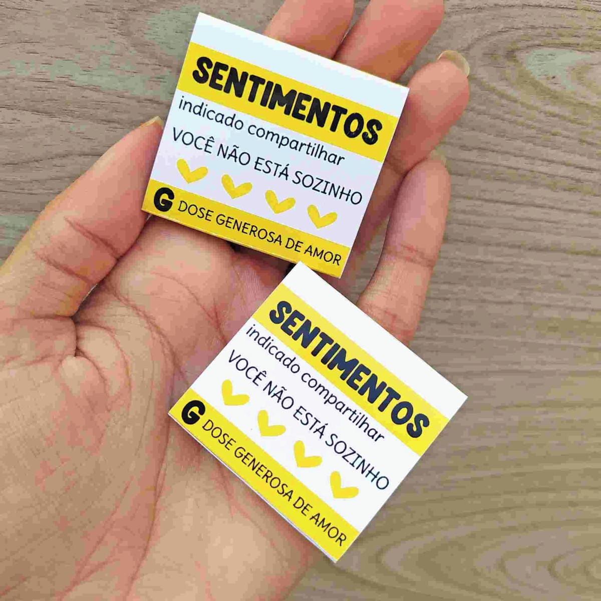 Kit Setembro Amarelo Digital com PNG para Imprimir 4 Mão segura dois pequenos papéis impressos com textos e corações amarelos.