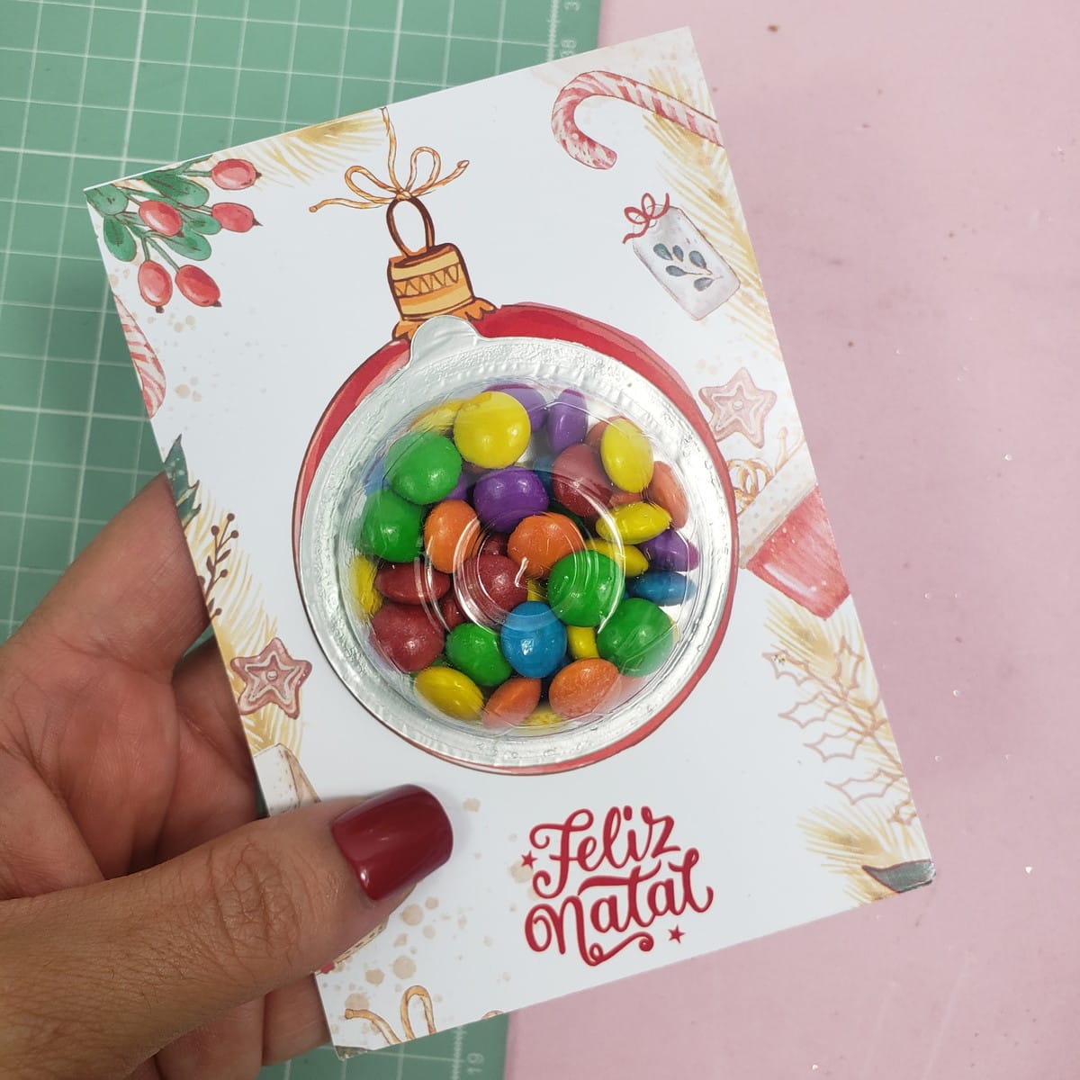 Lembrancinhas de Natal para Clientes prontas para Imprimir 2 Mão segura cartão impresso com ilustração natalina e doces coloridos encapsulados.