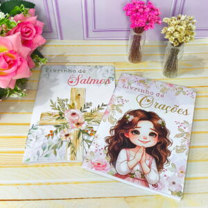 Dois livrinhos religiosos com capas ilustradas, um com cruz floral e outro com menina orando.