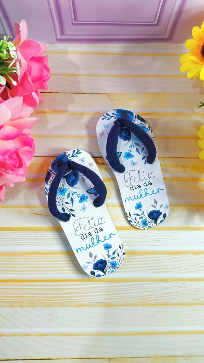 Chinelinho Dia da Mulher Arquivo PNG para Sublimação 5 Duas sandálias brancas com estampa floral azul e a mensagem 'Feliz dia da mulher'.