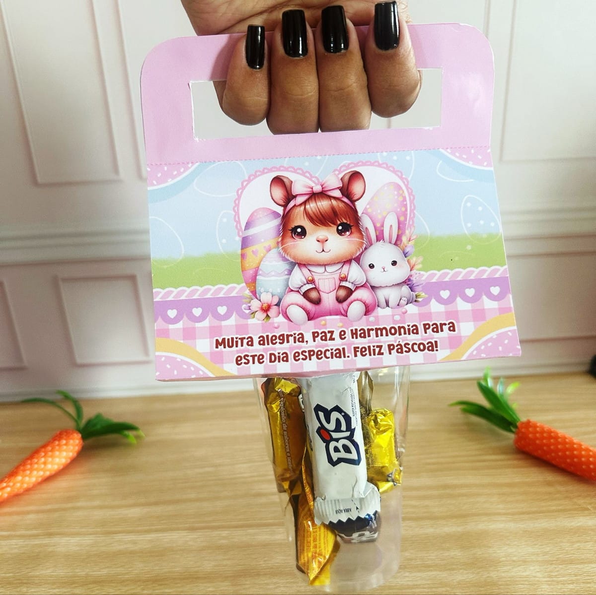 Mimos de Páscoa Capivara Kit Digital para Corte e Impressão 4 Mão segurando sacola de presente rosa com arte digital de coelhos e doces.