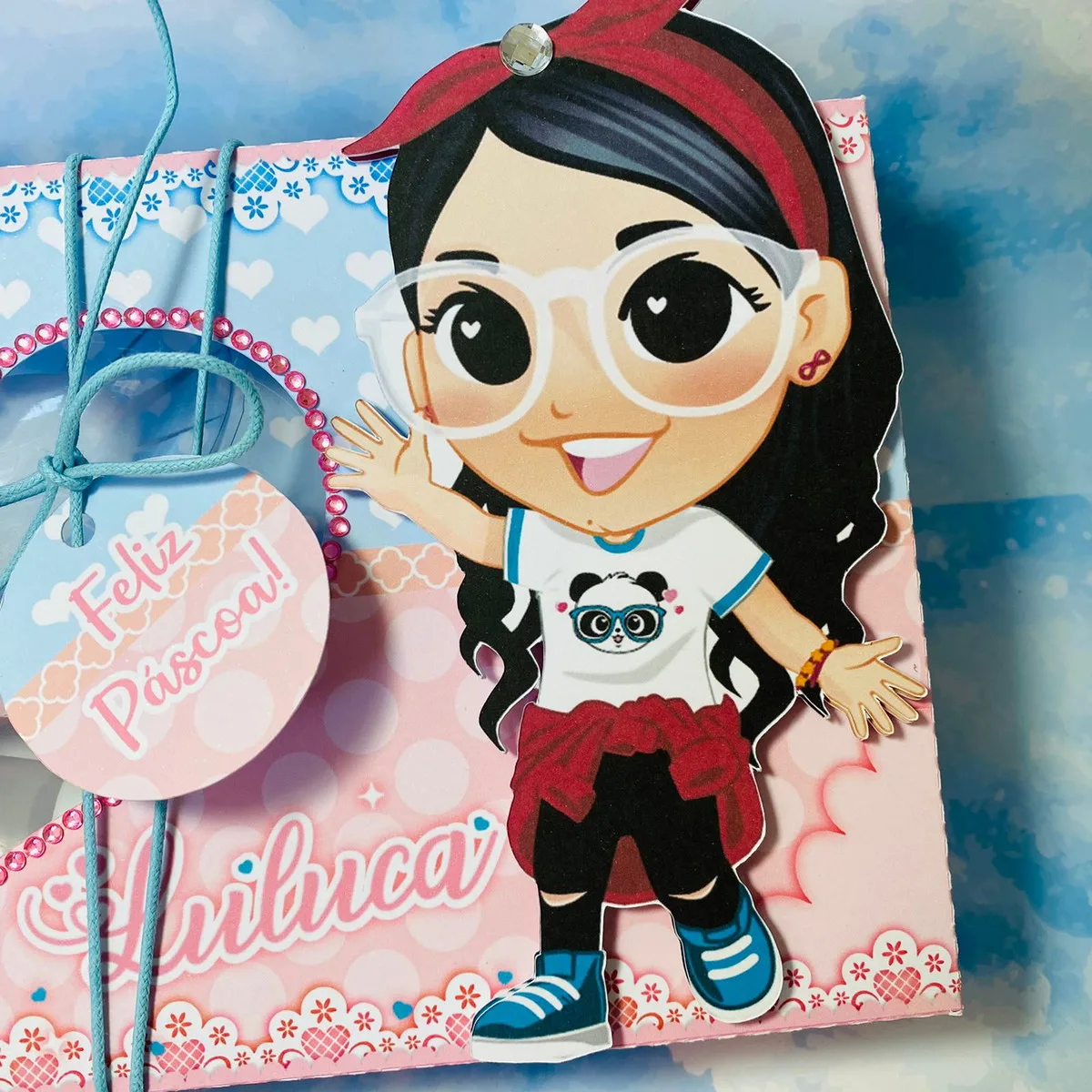 Caixa decorada com desenho de menina e etiqueta escrita Feliz Páscoa.