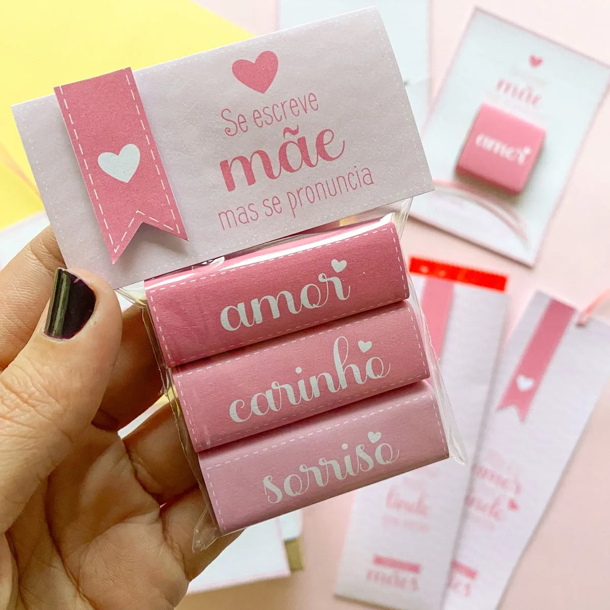 Mão segurando embalagem rosa decorada com mensagens carinhosas e corações.