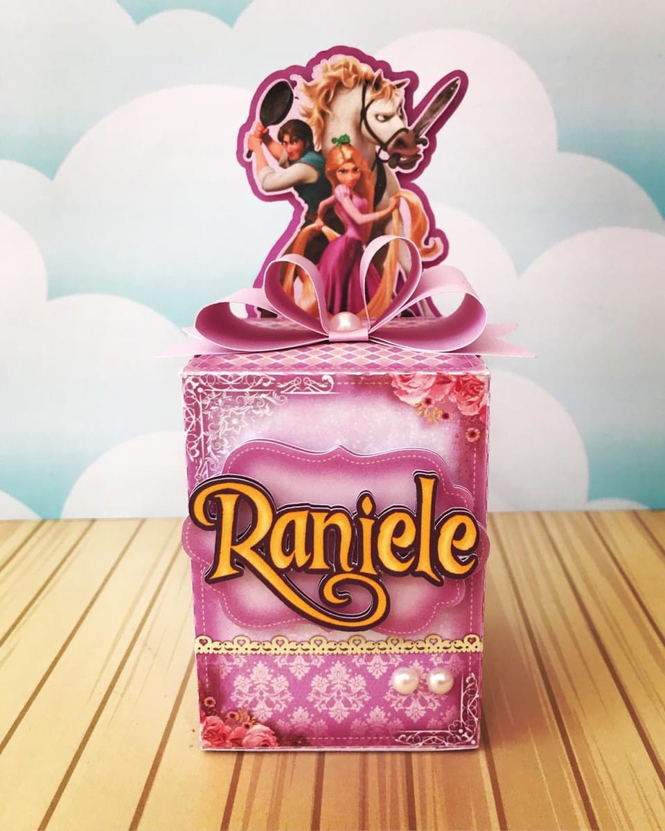 Kit Digital Festa Rapunzel com Caixas Sacolas e Convites 4 Caixa decorativa rosa com personagens de conto de fadas. Laço e pérolas adornam o item.
